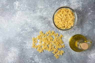 Bir kase çiğ farfalle makarna ve mermer arka planda bir şişe zeytin yağı. Yüksek kalite fotoğraf