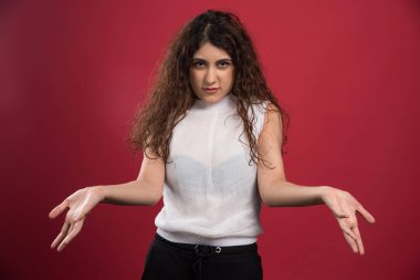 Gülümseyen kadın ellerini kırmızı arka planda gösteriyor.