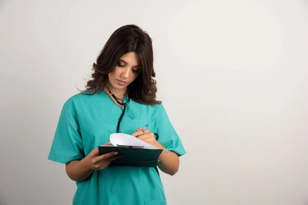 クリップボードからノートを読んで聴診器を持つ女性医師 高品質の写真 — ストック写真