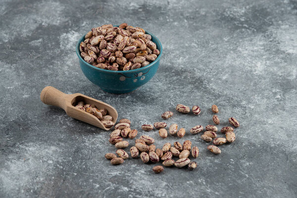 Bowl of dry beans and wooden spoon on marble background. High quality photo