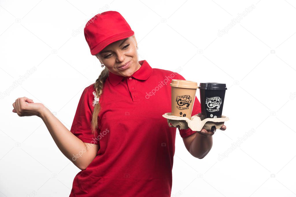 Woman courier holding two cups of coffees on white background. High quality photo
