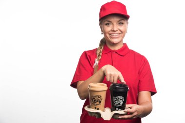 Kırmızı üniformalı kadın elinde beyaz arka planda iki fincan kahve tutuyor. 