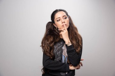 Gri arkaplanı düşünen baskılı sweatshirt giyen genç bir kız. Yüksek kalite fotoğraf