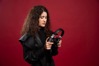 Kıvırcık kadın kırmızı arka plandaki kulaklıklara bakıyor. Yüksek kalite fotoğraf