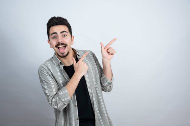 Sakallı adamın portresi beyaz duvarın arkasında bir yeri işaret ediyor. Yüksek kalite fotoğraf