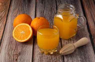 Tahta bir masada cam bir kavanozda taze portakal suyu.