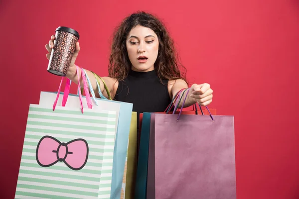 Vrouw Met Beker Tonen Haar Aankopen Rode Achtergrond — Stockfoto