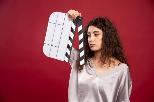 Brunette Woman Looking Clapperboard Red Background High Quality Photo — Stock Photo, Image