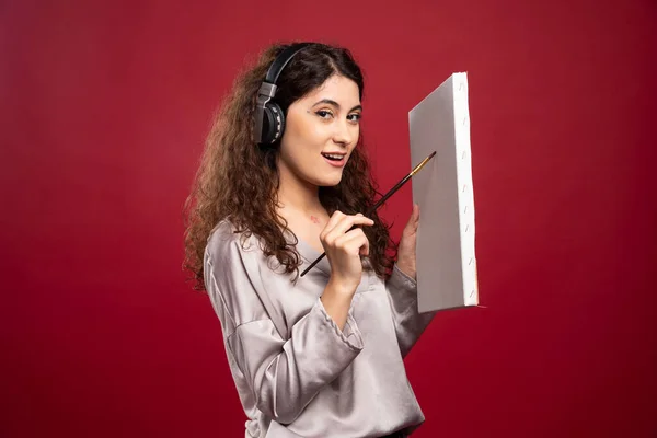 Γυναίκα Ακουστικά Ζωγραφική Καμβά Πάνω Από Κόκκινο Φόντο Υψηλής Ποιότητας — Φωτογραφία Αρχείου