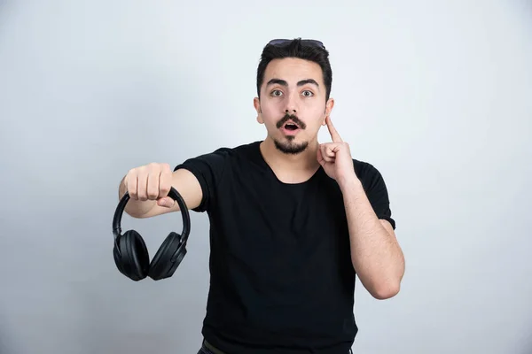 Brunetka Człowiek Model Stoi Trzyma Słuchawki Pod Białą Ścianą Wysokiej — Zdjęcie stockowe