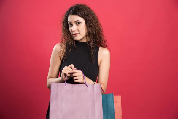 Vrouw Met Lastige Blik Houden Veel Van Tassen Rode Achtergrond — Stockfoto