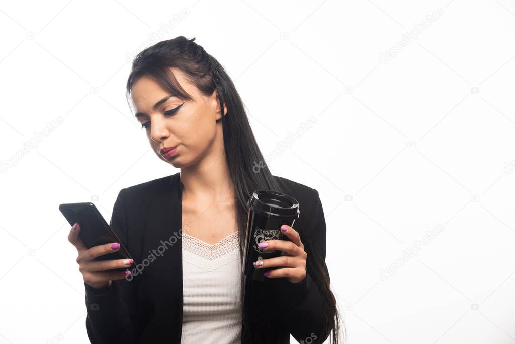Business woman holding a cup and cellphone on white background