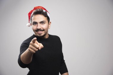 Gülümseyen adam Noel Baba 'nın kırmızı şapkasıyla kamerayı işaret ediyor. Yüksek kalite fotoğraf
