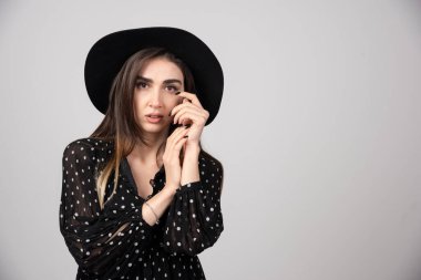 Siyah şapkalı esmer kadın gri arka planda duruyor. Yüksek kalite fotoğraf