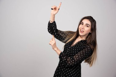 Gri arkaplandaki bir şeyi işaret eden kadın portresi. Yüksek kalite fotoğraf