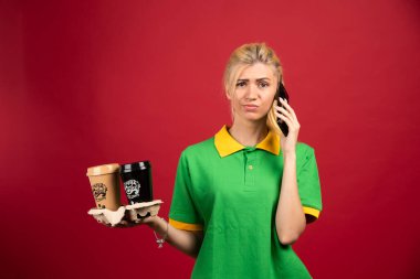 Sipariş alırken elinde iki fincan kahve tutan kadın kurye. Yüksek kalite fotoğraf