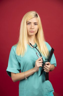 Sarı doktor kırmızı arka planda pano ile poz veriyor. Yüksek kalite fotoğraf