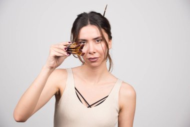 Gri arka planda boya fırçası gösteren güzel bir kadın. Yüksek kalite fotoğraf