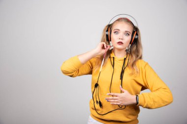 Kulaklıklı sarışın kadın gri arka planda şaşırıyor. Yüksek kalite fotoğraf