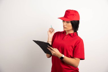 Güzel kurye beyaz arka planda duran panoya bakıyor. Yüksek kalite fotoğraf