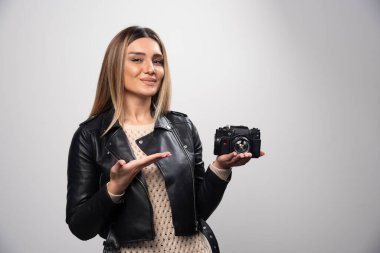 Deri ceketli bir kız zarif ve olumlu pozlarda fotoğraflarını çekiyor. Yüksek kalite fotoğraf