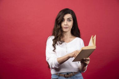 Kırmızı arka planda duran kitap okuyan kadın. Yüksek kalite fotoğraf