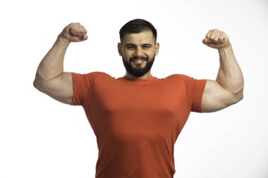 Kırmızı gömlekli sporcu kol kaslarını gösteriyor ve kendinden emin görünüyor. Yüksek kalite fotoğraf