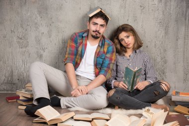 Yerde bir sürü kitapla oturan güzel bir çift resmi. Yüksek kalite fotoğraf