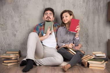 Kitapları tutan ve kameraya bakan sevimli bir çift. Yüksek kalite fotoğraf