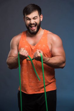 Koyu mavi arka planda spor olsun diye lastik tutan genç adam. Yüksek kalite fotoğraf