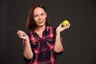 Sonbahar kış koleksiyonu giysileri içinde elinde bıçak ve yeşil elma tutan bir kadın model. Yüksek kalite fotoğraf