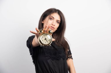 Beyaz arka planda saati tutan genç bir kadın. Yüksek kalite fotoğraf