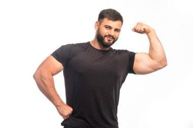 Siyah gömlekli sporcu kol kaslarını gösteriyor. Yüksek kalite fotoğraf