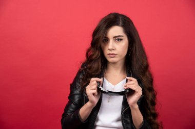 Kırmızı arka planda siyah gözlüklü genç bir kadın. Yüksek kalite fotoğraf