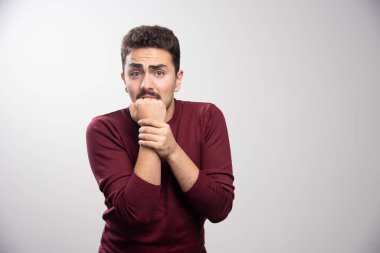 Gri duvardan korkan esmer bir adam. Yüksek kalite fotoğraf