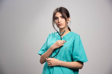 Gri arka planda duran üniformalı kadın doktor. Yüksek kalite fotoğraf