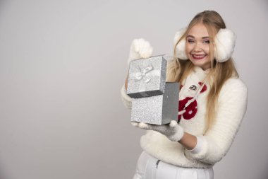 Beyaz kulaklıklı güzel bir kadın hediye kutusunun içine bakıyor. Yüksek kalite fotoğraf