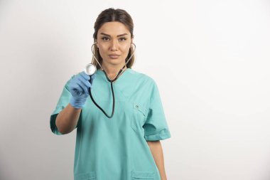 Beyaz arka planda steteskobu olan genç bayan hemşire.
