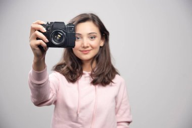 Gri arka planda fotoğrafını çeken kadın fotoğrafçı. Yüksek kalite fotoğraf