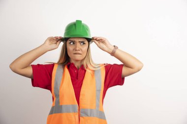 Beyaz arka planda kaskla poz veren bir kadın işçinin portresi. Yüksek kalite fotoğraf