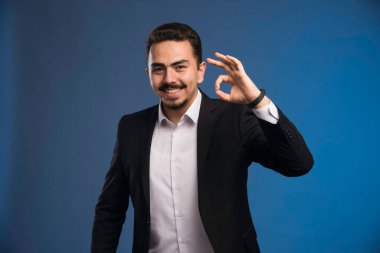 Siyah takım elbiseli bir işadamı olumlu bir işaret veriyor. Yüksek kalite fotoğraf