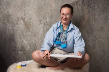 Kadın mermer zeminde tuval ve fırçayla oturuyor. Yüksek kalite fotoğraf