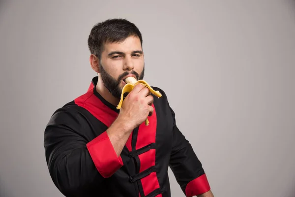 Giovane Che Mangia Una Banana Sfondo Grigio Foto Alta Qualità — Foto Stock