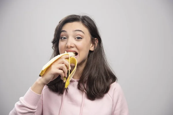 Junge Frau Isst Banane Vor Grauem Hintergrund Hochwertiges Foto — Stockfoto