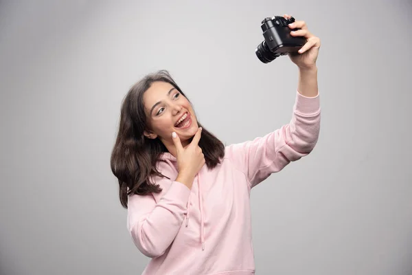 Ładna Młoda Kobieta Robi Sobie Selfie Kamerą Nad Szarą Ścianą — Zdjęcie stockowe