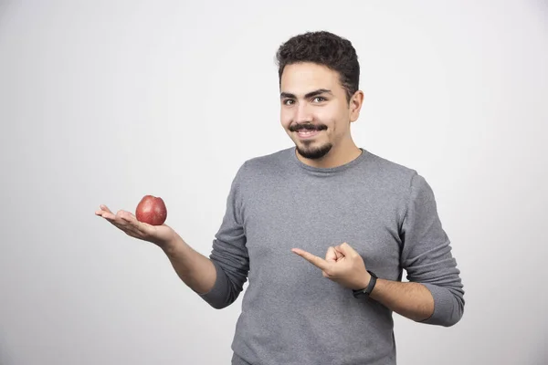 Bruneta Muž Ukazuje Červené Jablko Šedém Pozadí Kvalitní Fotografie — Stock fotografie