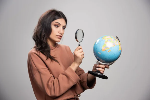 拡大鏡で地球を見ているブルネットの女性 高品質の写真 — ストック写真