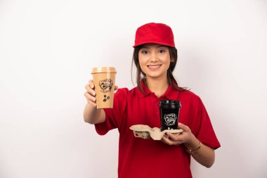 Kırmızı üniformalı kadın beyaz arka planda iki fincan kahve tutuyor. Yüksek kalite fotoğraf