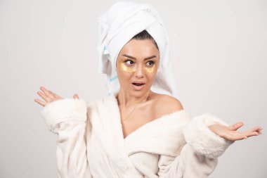 Bornoz ve kozmetik göz bantları takan genç bir kadın. Yüksek kalite fotoğraf