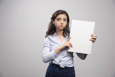 Esmer ressam tuvali tutuyor ve somurtuyor. Yüksek kalite fotoğraf